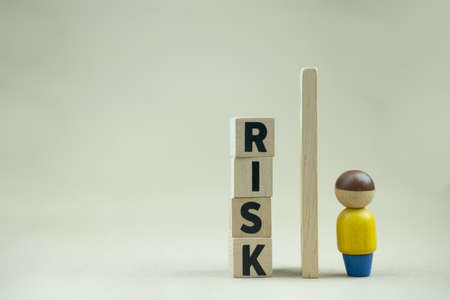 A human figure stands near a pile wood block text of RISK. Business, Risk Management, Solution, Insurance and strategy Conceptsの写真素材