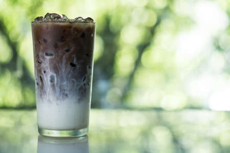 Iced coffee shows the texture milk and coffee in a glass cup against nature background.の写真素材