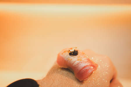 Fresh tuna sushi sprinkle with golden leaf and Japanese chef put the sushi onto on the back hand....