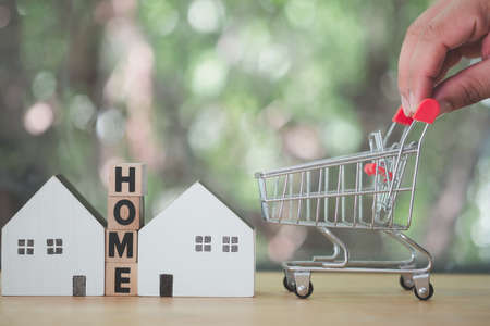 Hands holding mini shopping trolley for buy home. The concept of buying or renting a house, apartment. Home purchase for the bestの写真素材