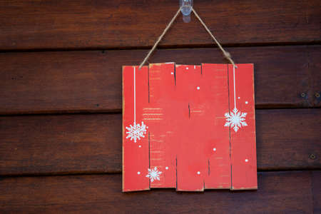 A blank red wood sign hanging on antique rustic wooden background. Holiday background with copy spaceの写真素材