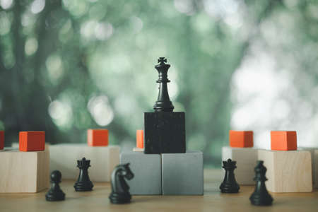 Stand of black king chess stand on wood block. Winner of business competition and marketing strategy planning concept.の写真素材