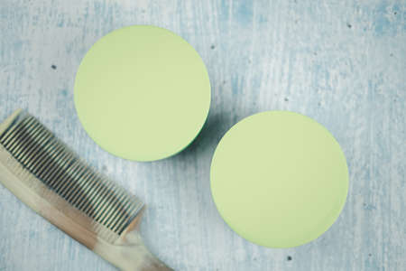 Hair mask in plastic green box and brown comb on blue background.の写真素材