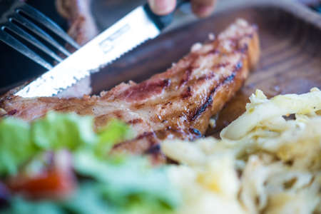 Selective focus in a man eating grilled steak at restaurantの写真素材