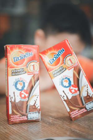 Bangkok - January 16, 2022 : A box of Ovaltine UHT milk chocolate which is distributed by the AB FOOD & BEVERAGES (THAILAND) LTD. and blur of boy background on the table.のeditorial素材
