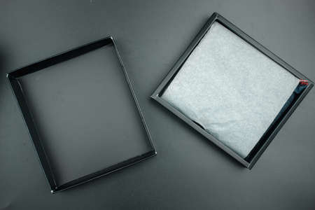 Opened a black cardboard box with thing inside on a black background.
