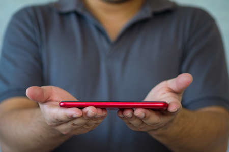 Hands holding red smartphone. Close up