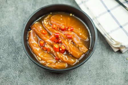 Fresh salmon raw pickled in shoyu sauce or soy sauce  in Korean style food in a black bowl