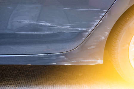 A car gray with a scratch on bumper and door. Close upの写真素材