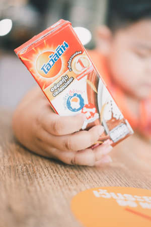 Bangkok - January 25, 2022 : A box of ready to drink milk Thai Brand, Ovaltine chocolate on baby hand. Close upのeditorial素材