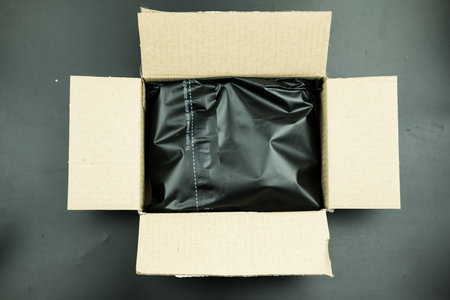 Plastic black bag covering the parcel out for protection product cracked or insurance during transit in brown carton box. Ecommerce shipment service conceptの写真素材