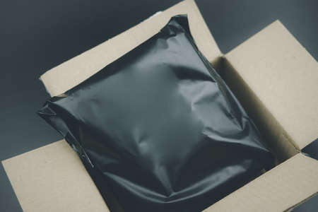 Plastic black bag covering the parcel out for protection product cracked or insurance during transit in brown carton box. Ecommerce shipment service conceptの写真素材