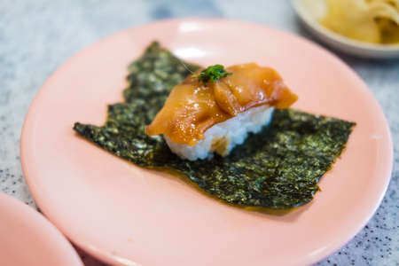 Single-serve sushi made of squid placed on seaweed plate and pink dishの写真素材
