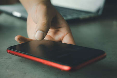 Man hands in red phone, using a touch screen smart phone.の写真素材