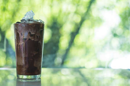 Iced coffee in tall glass with milk against nature background.の写真素材