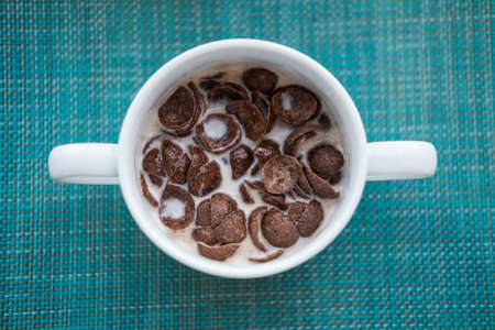 Chocolate corn flakes in bowl with milk. Healthy breakfast concept. Top view.の写真素材