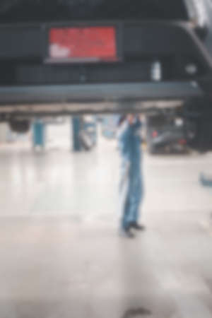 Blurred no focus background of car mechanic are checking cars. Blur image of young employees who are checking engines. Concept of quality inspection of cars Engine maintenance all the time.の写真素材