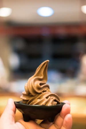 Human hand holding twisted ice cream chocolate. close up