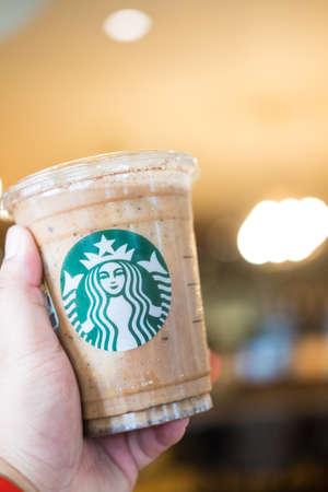 Bangkok, Samut Prakan - May 29, 2022 : Holding a cup of Almondmilk White Chocolate Affogato Frappuccino from Starbucks coffee. Starbucks is the world's largest coffeehouse and is highly popularのeditorial素材