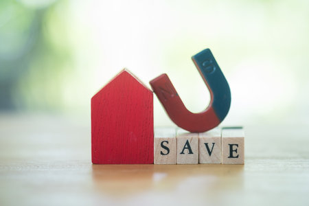 U shape magnet put on the top wooden block cube with text SAVE and red home on sunlight in the nature. The concept of motivation to save money to buy homeの写真素材