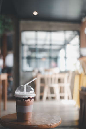 Ice cold coffee mocha in plastic glass on wood table at coffee shop. Refreshing drinkの写真素材