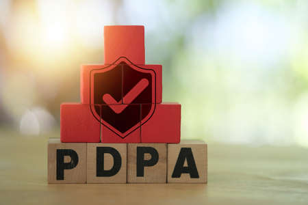 Shield with check mark icon on red wood placed block on PDPA word written on wood block. Protection from data theft privacy.の写真素材