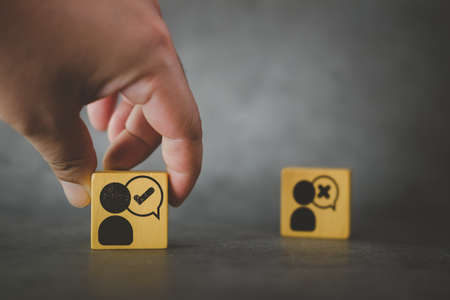Hand choose man with tick mark icon on wooden cube block. The concept of choose of smart people to organization, decision making, approval or voting.の写真素材