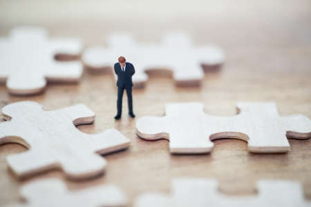 Businessman standing and jigsaw puzzle pieces thinking, using as thinking business plan and how to...