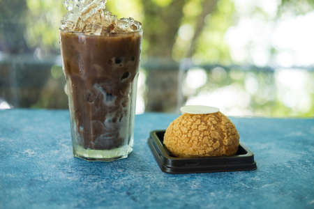 Fresh baked choux pastry cakes with a glass of iced Mocha coffee at cafe.