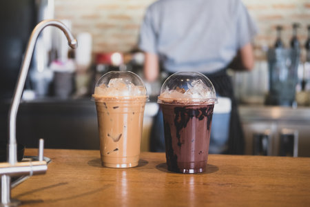 Iced chocolate and iced mocha on table with blurred back view of baretta at coffee shopの写真素材