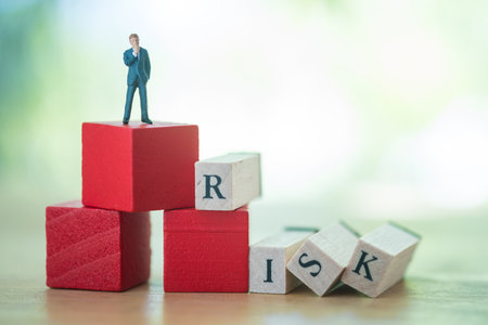 Miniature people businessman standing with wood word RISK using as background business concept and...