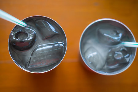 Water with ice in a metal glass on a wooden table at a local Thai restaurantの写真素材