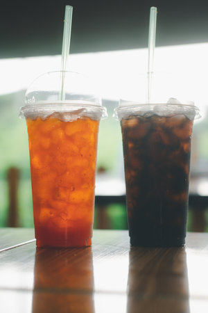 Iced black coffee and Thai tea in plastic glass on wood table