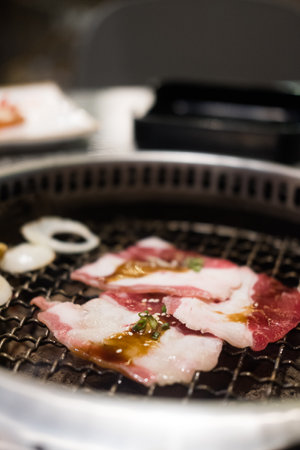 Yakiniku grilling meat on metal grill pan over charcoal stove. Close upの写真素材