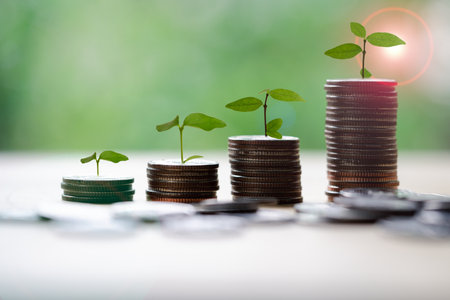 Save money for prepare in the future. Tree growing on coin of stacking coins with green bokeh...