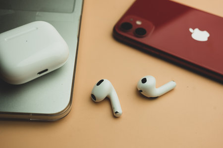 Bangkok, Thailand - November 19, 2022 : Apple AirPods (3rd generation) with wireless charging case and next to red Iphone 11のeditorial素材