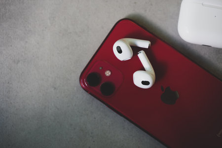 Bangkok, Thailand - November 19, 2022 : AirPods 3 Bluetooth headphones placed on red Iphone 11. Top viewのeditorial素材