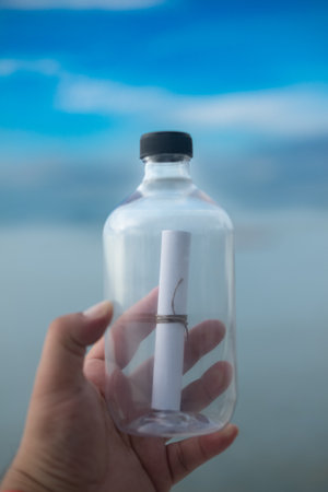 Lovely message in the bottle against the sky and sea background in hand.
