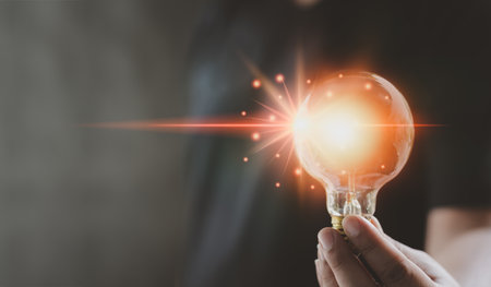 Hand of man holding illuminated light bulb, idea, concept creativity with bulbs that shine glitter....