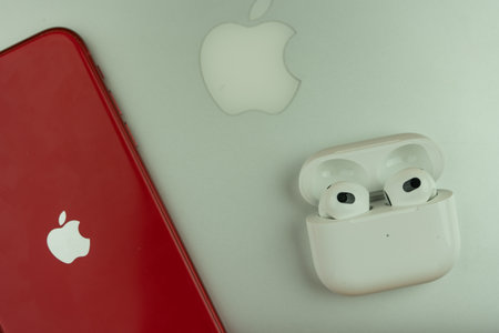 Bangkok, Thailand - November 28, 2022 : New Apple AirPods 3 and charging case next to iPhone 11 product red model place on MacBook pro. Top viewのeditorial素材