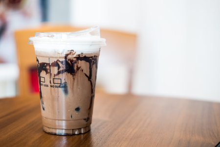 Iced mocha, coffee and cocoa powder mixed with sweetened condensed milk and fresh milk top with soft milk froth and cocoa powder in a takeaway plastic glass, showing texture of chocolate sauceの写真素材