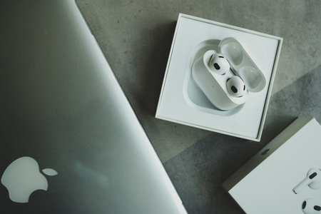 Bangkok, Thailand - December 10, 2022 : Apple AirPods 3 and charging case in box with a grey Macbook Pro.のeditorial素材