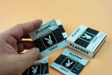 Samut Prakan, Thailand - December 10, 2022 : Man hand holding PLAYBOY Condom size 52 mm, (Playboy Black Tie) PLAYBOY brand condoms. Condom, uneven surface.のeditorial素材