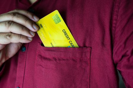 Cropped close up shot photo of businessman in a red shirt pick up credit card of shirt pocket while...
