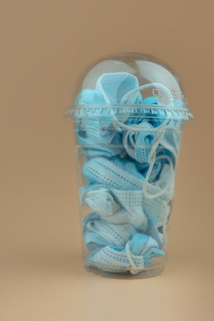 Folded used protective face mask into plastic glass. Protection before littering for prevent spread...