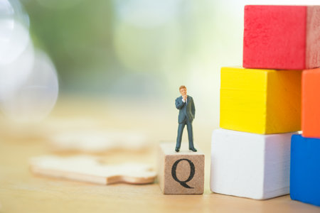 Miniature businessman thinking and standing on Q. The concept of thinking for an answer, using as business goals or future thinking.の写真素材
