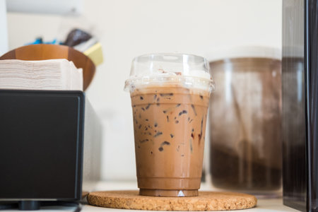 Close up view of ice Mocha coffee in take away cup. on wood counter table in coffee shopの写真素材