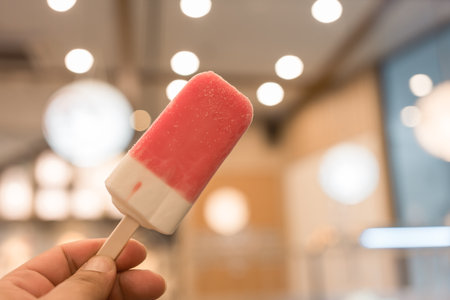 Colorful tasty ice cream stick in hand with bokeh background. Close upの写真素材