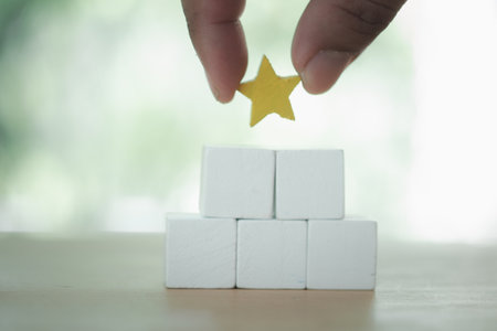 Hand putting star shape on top of the empty white wood block. The best excellent services rating customer experience concept. Customer evaluation survey and satisfaction concept.の写真素材