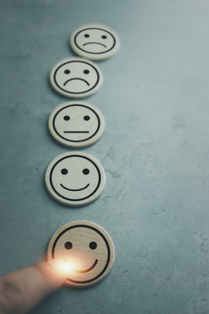 Hand of a man chooses a smiley face icon on wood block cube, The best excellent business services rating customer experience, Satisfaction survey concept, Service ratingの写真素材